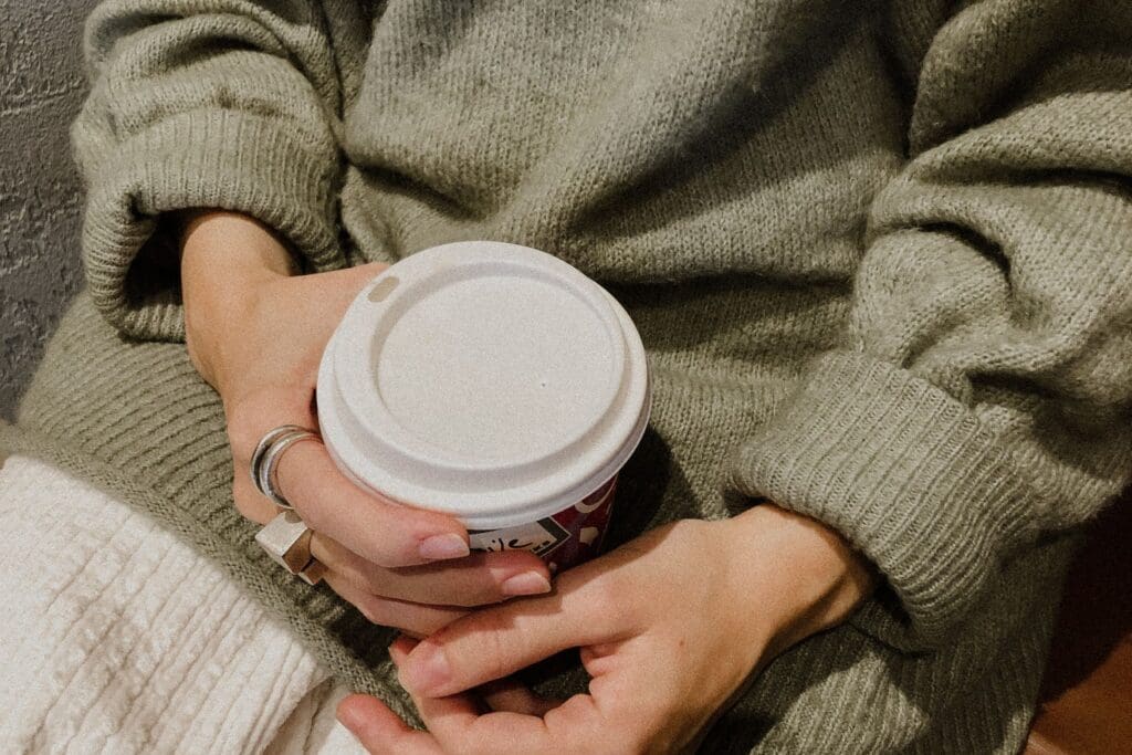 Person holding a warm cup, evoking comfort, care, and the beginning of healing