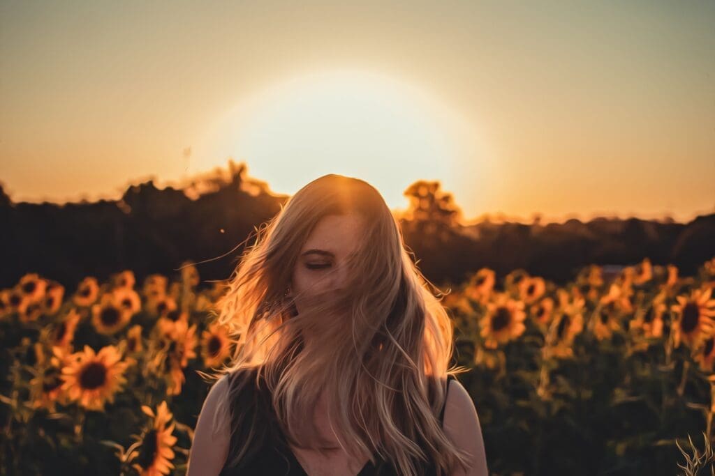 Woman in front of a sunflower field at sunset