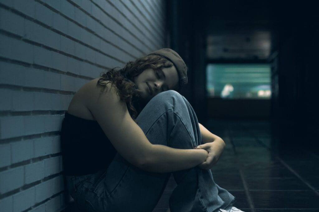 Woman sitting alone in a dark hallway at night, reflecting isolation and disconnection