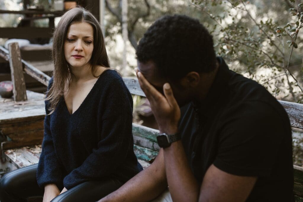 Couple sitting on a bench outdoors having a tense emotional conversation