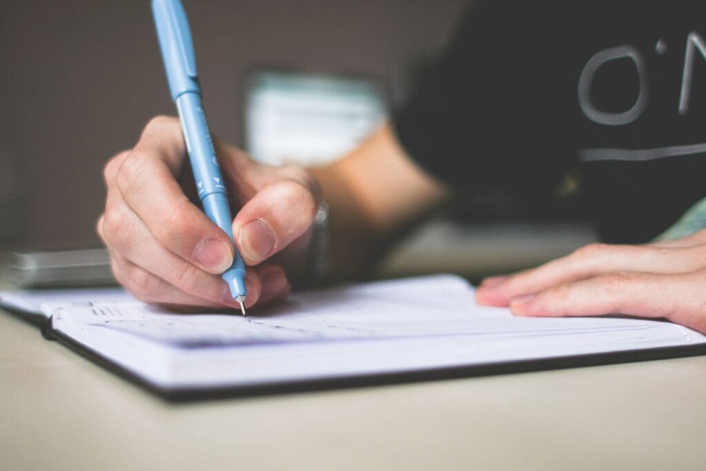 Person writing in a notebook, representing self-reflection and the process of understanding personal healing patterns