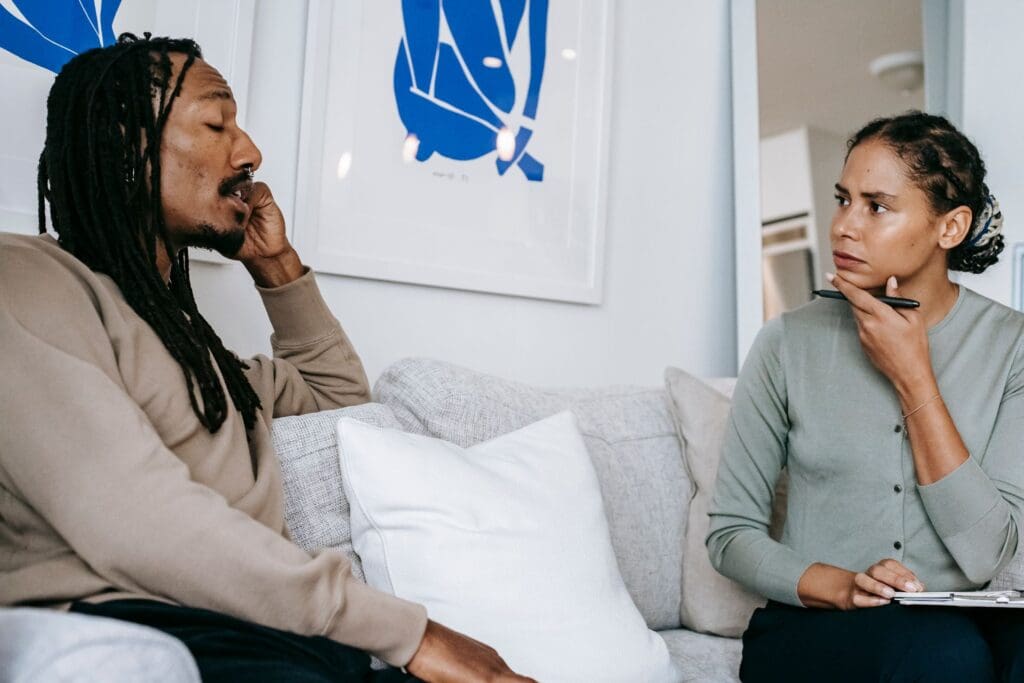 Therapist listening attentively to a client during a therapy session, representing trauma-informed care for self-medicating