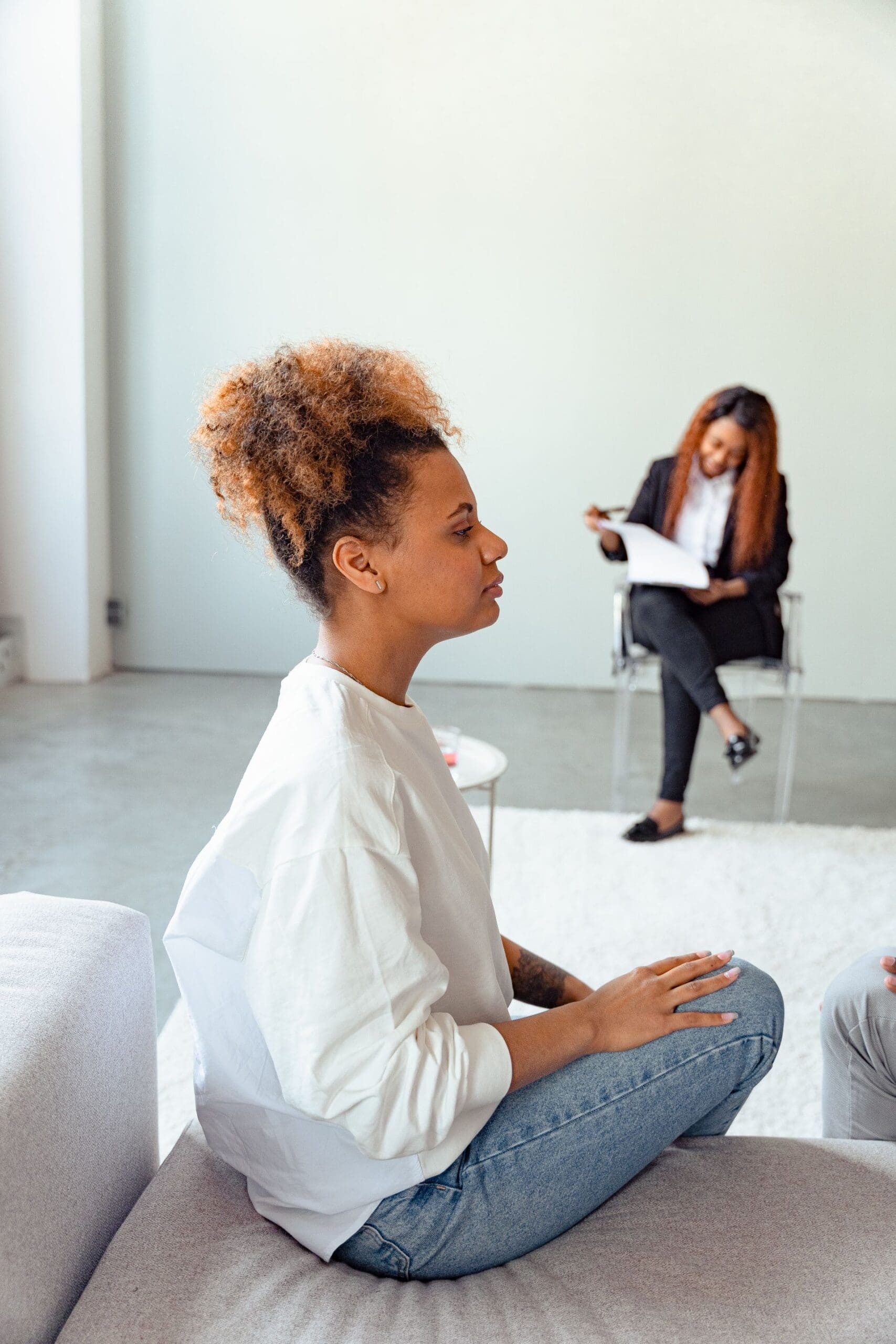 Woman sitting in a therapy session on a couch, representing the beginning of understanding self-medicating patterns