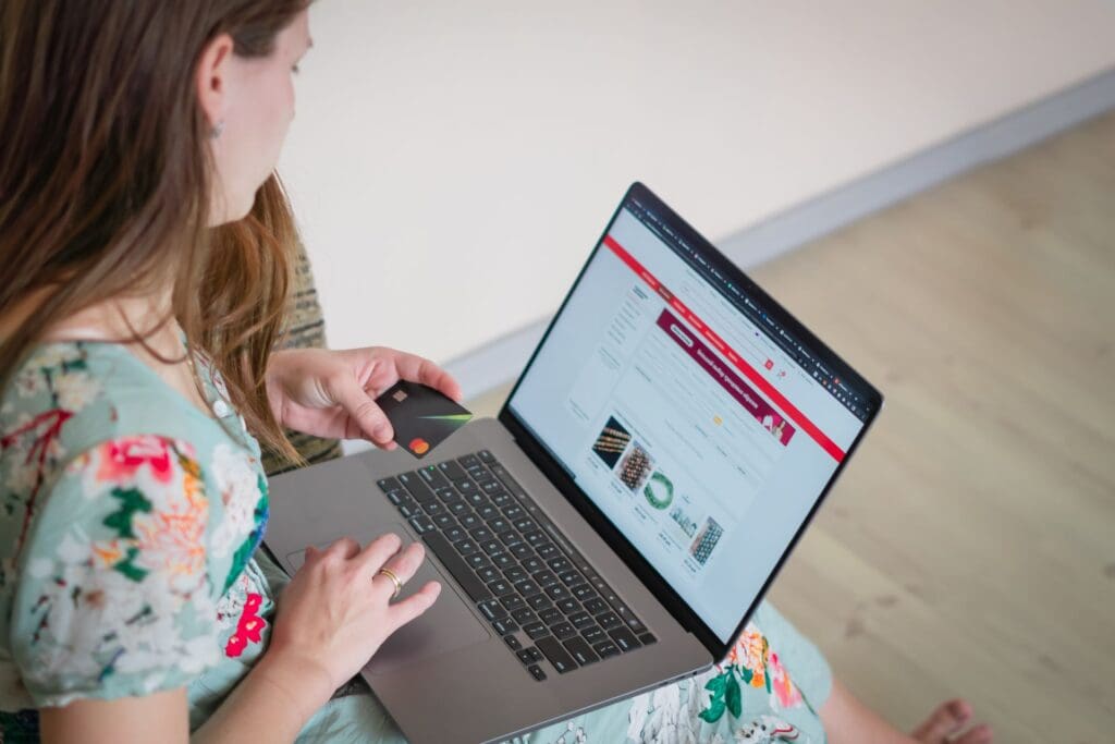 Woman holding a credit card while shopping online on her laptop.